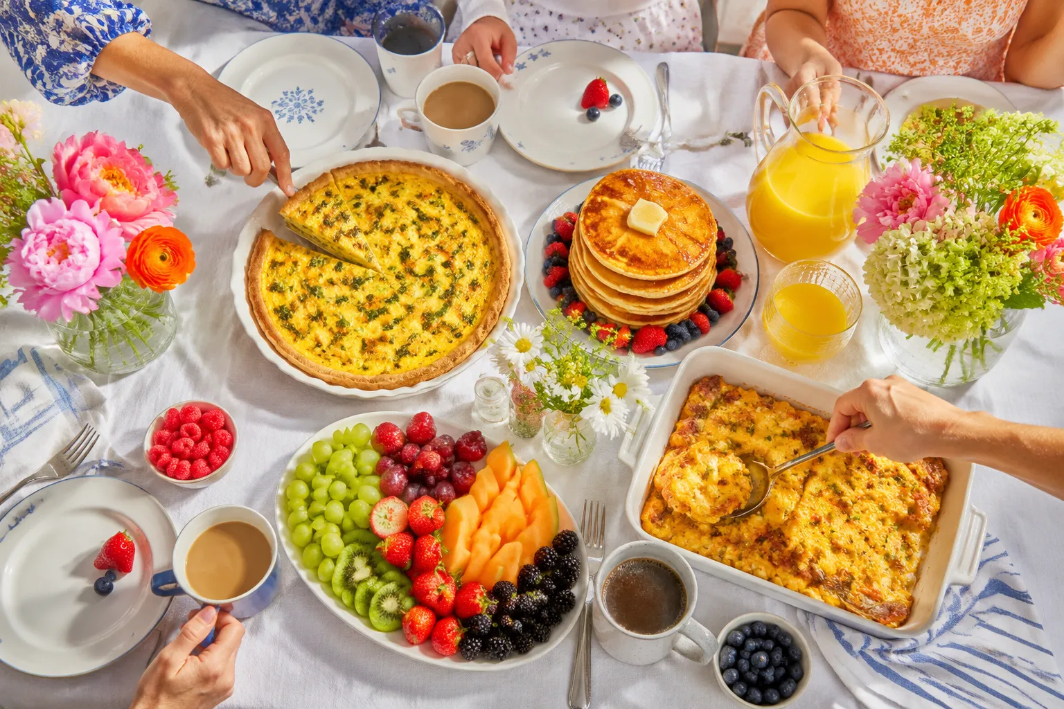 Brunch table with breakfast casserole, pancakes, quiche, and coffee