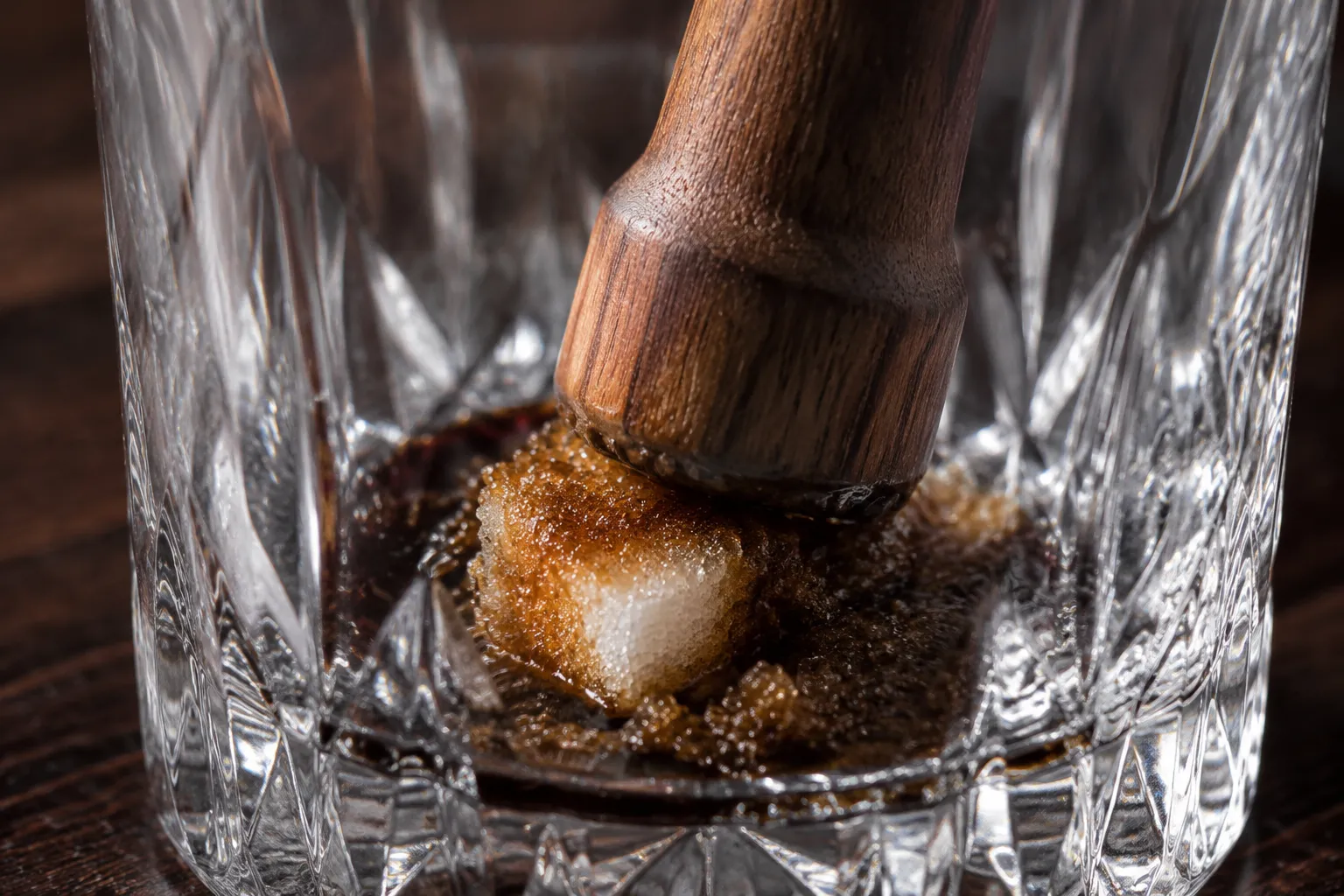 Muddling sugar cube and bitters for an old fashioned recipe