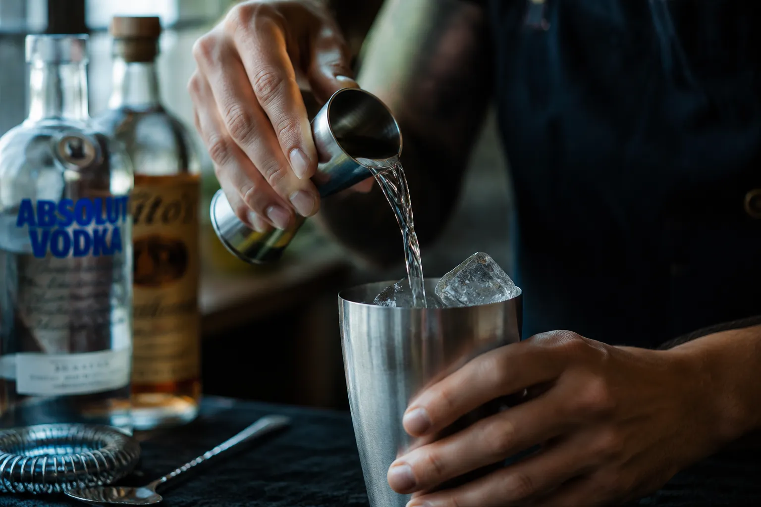 Pouring vodka into shaker for how to make a long island iced tea