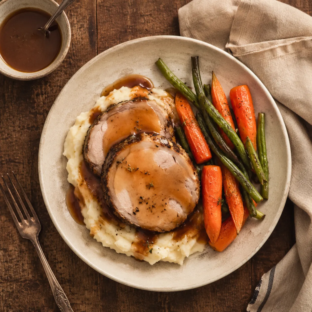 Pork roast dinner plated with mashed potatoes, vegetables, and gravy