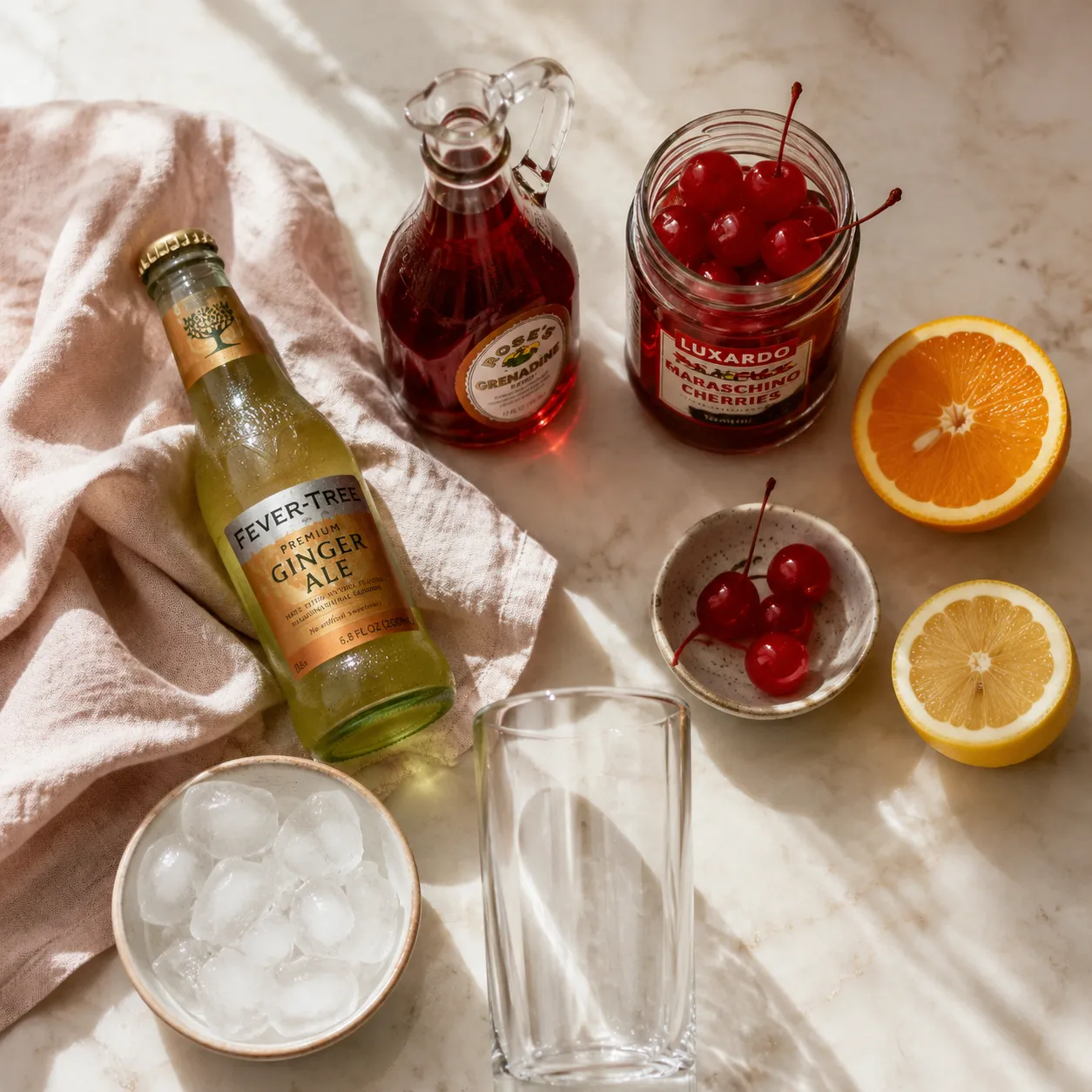 Shirley Temple drink ingredients flatlay with ginger ale, grenadine, and maraschino cherries