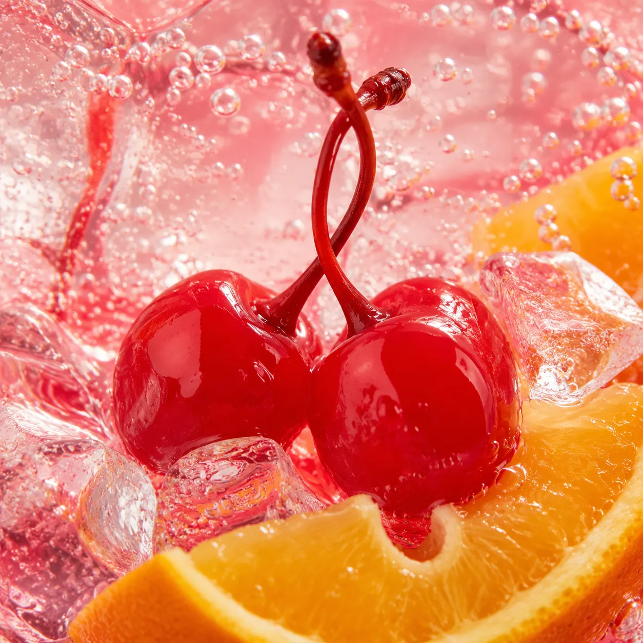 Close-up of maraschino cherries and orange garnish on a Shirley Temple drink