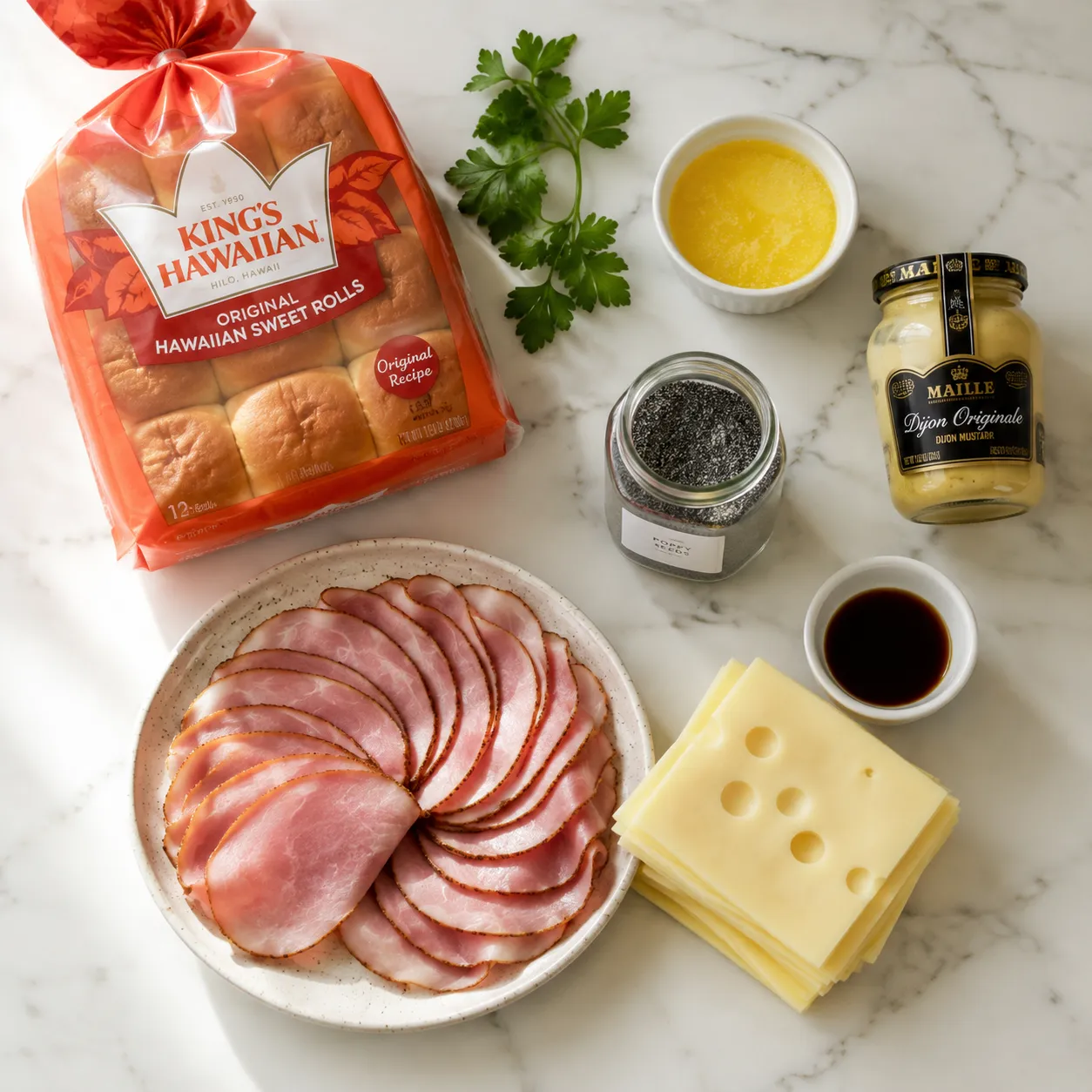 Ingredients for ham and Swiss sliders laid out on marble