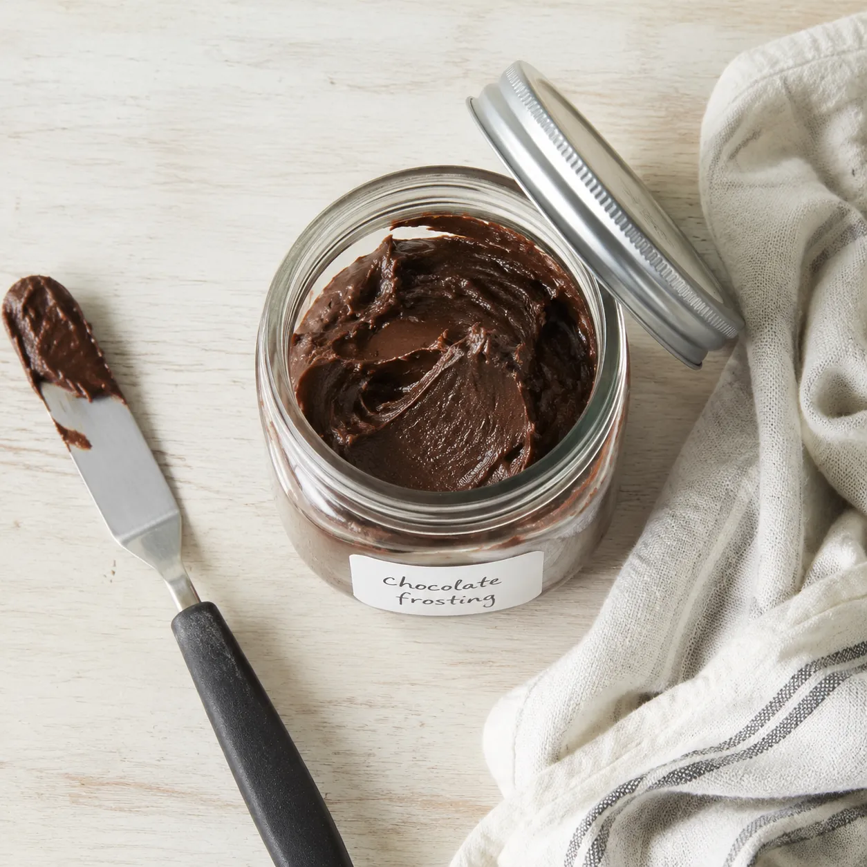 Homemade chocolate frosting stored in a glass jar for make-ahead use