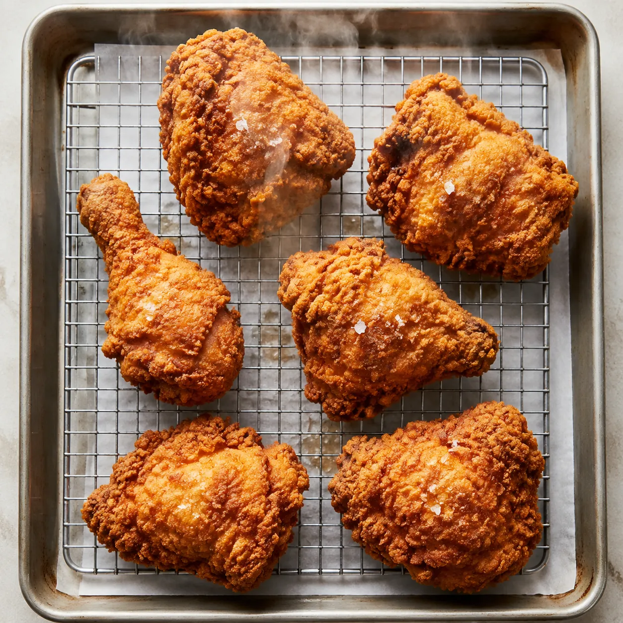 Crispy fried chicken resting on a wire rack after frying