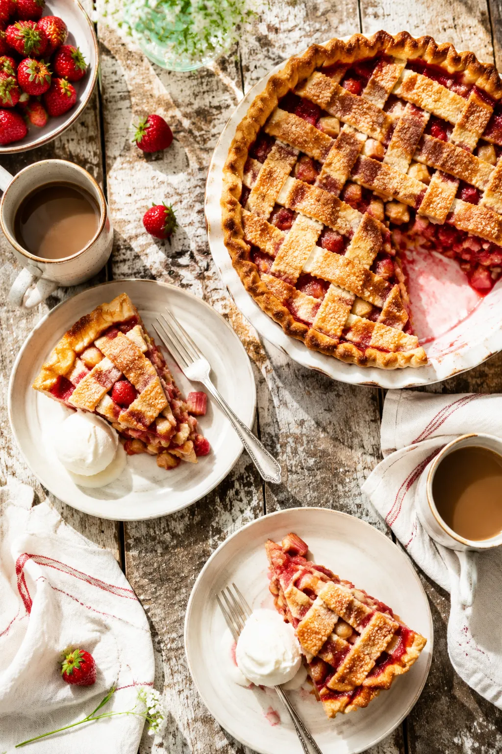 Strawberry rhubarb pie served on a rustic summer table with coffee.