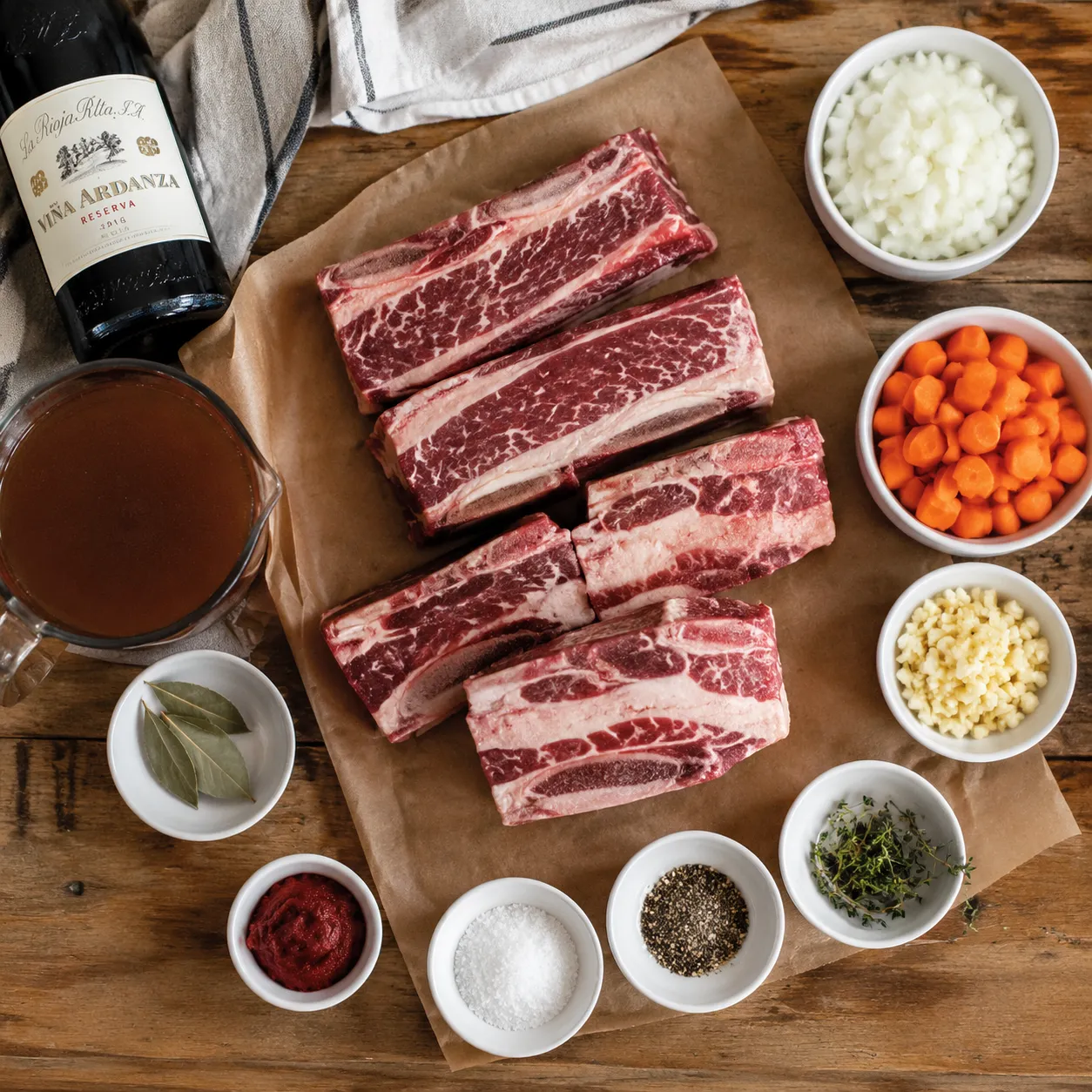 Beef short ribs recipe ingredients flatlay with red wine and aromatics
