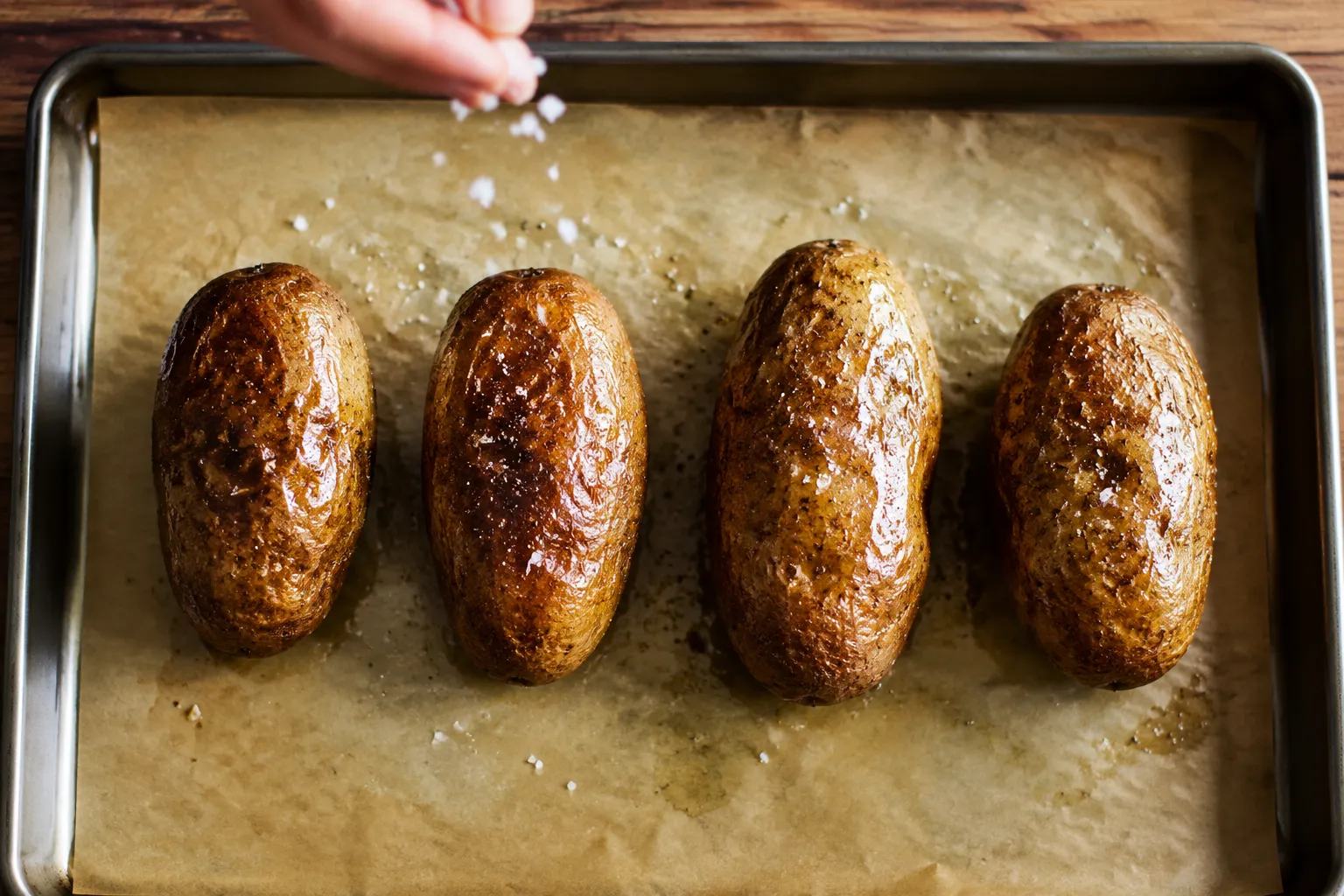 Seasoning russet potatoes with olive oil and kosher salt before baking