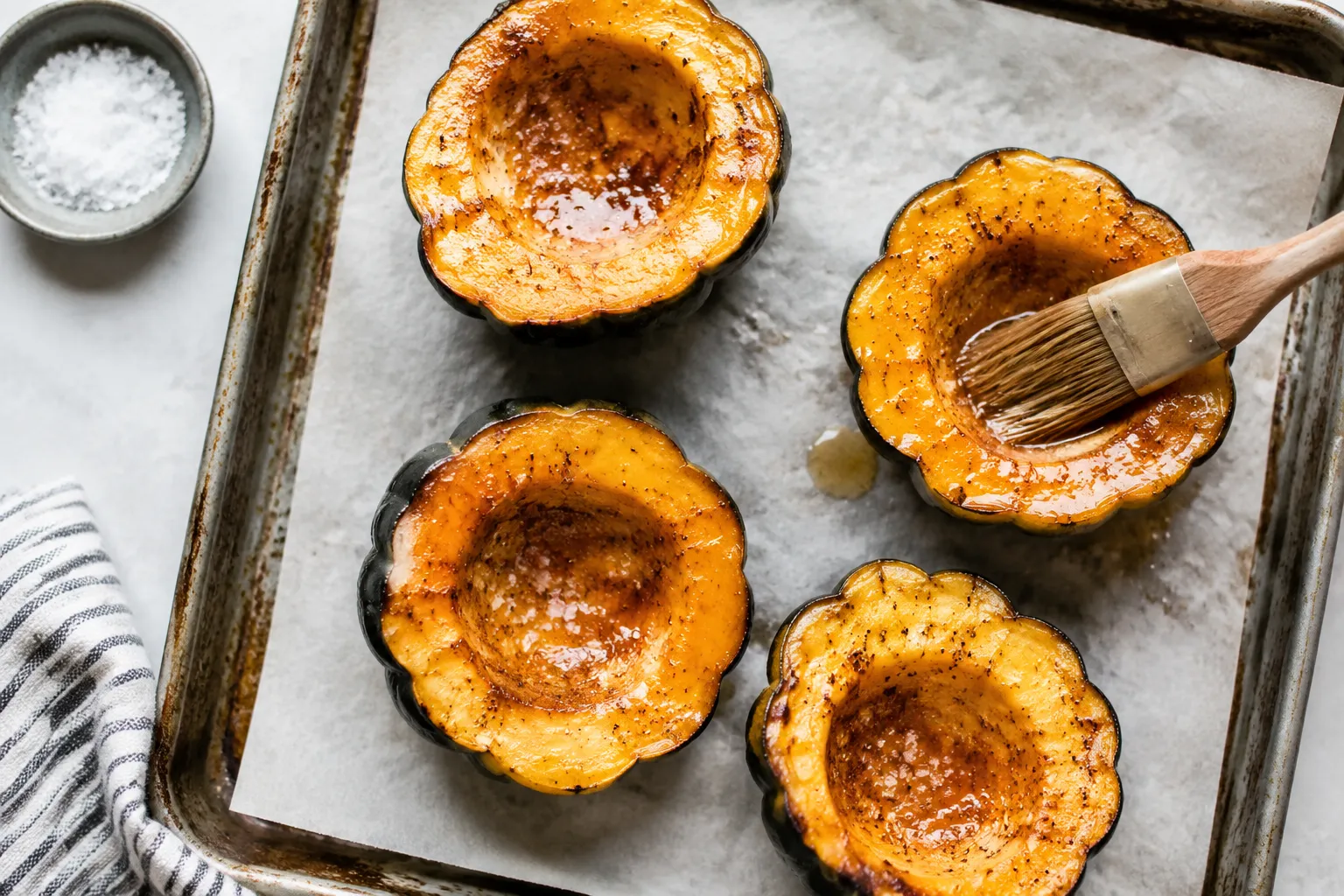 Acorn squash halves brushed with maple butter on a sheet pan