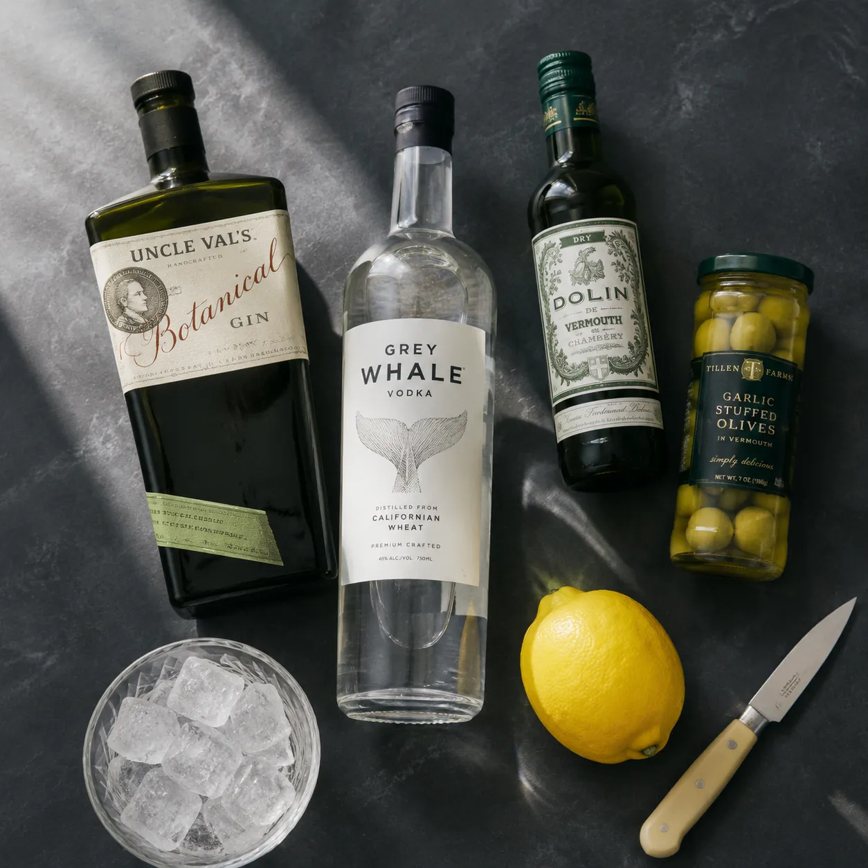 Martini recipe ingredients flatlay with gin, vodka, vermouth, and olives