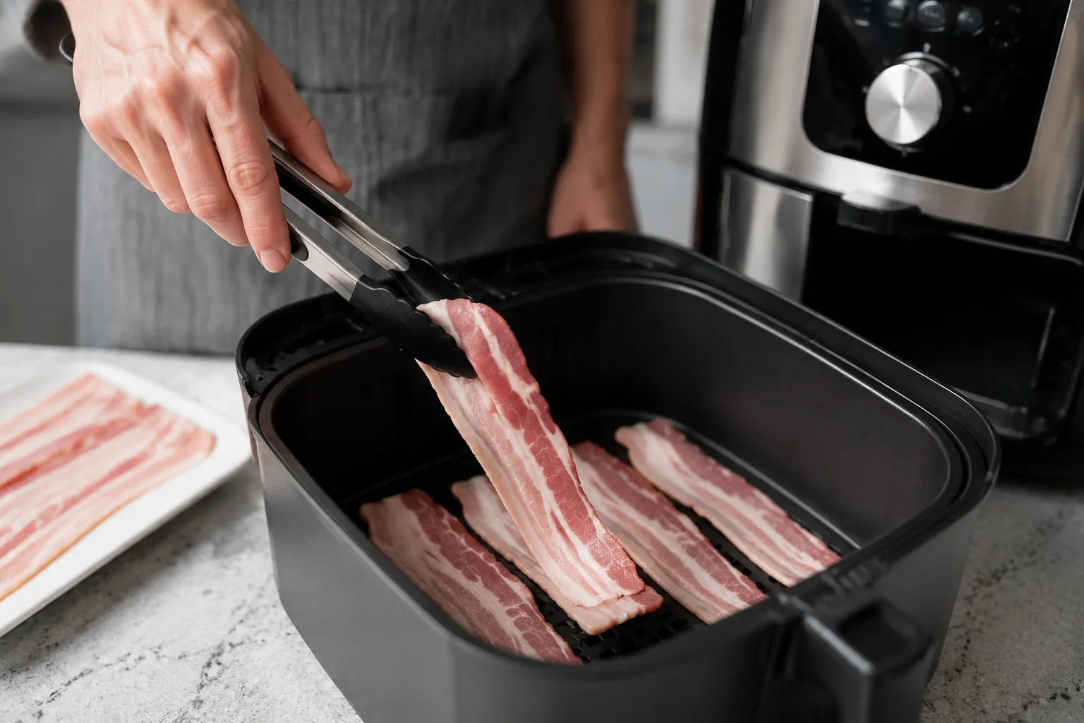 Placing raw bacon in single layer in the air fryer basket