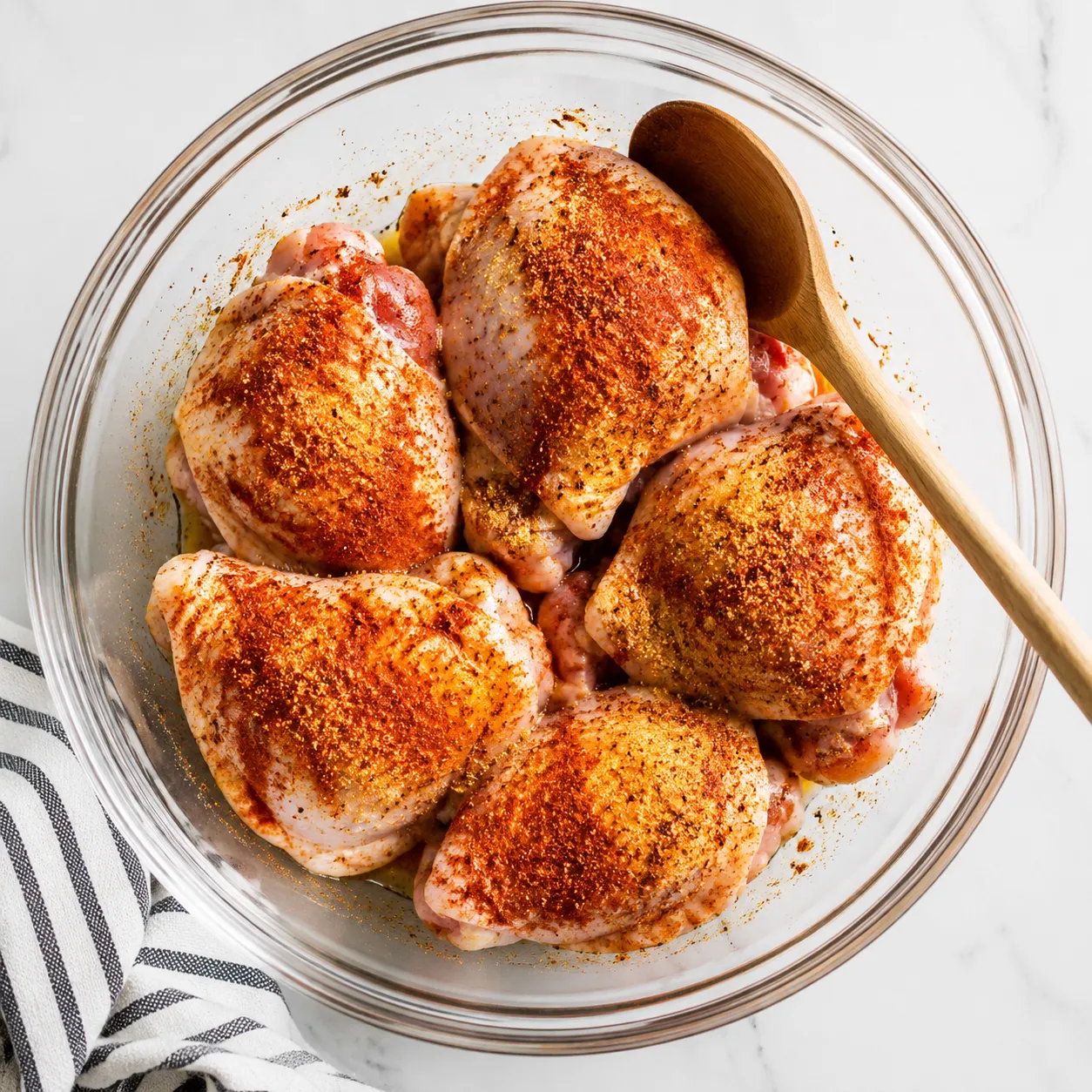 Seasoning chicken thighs with paprika and spices before baking