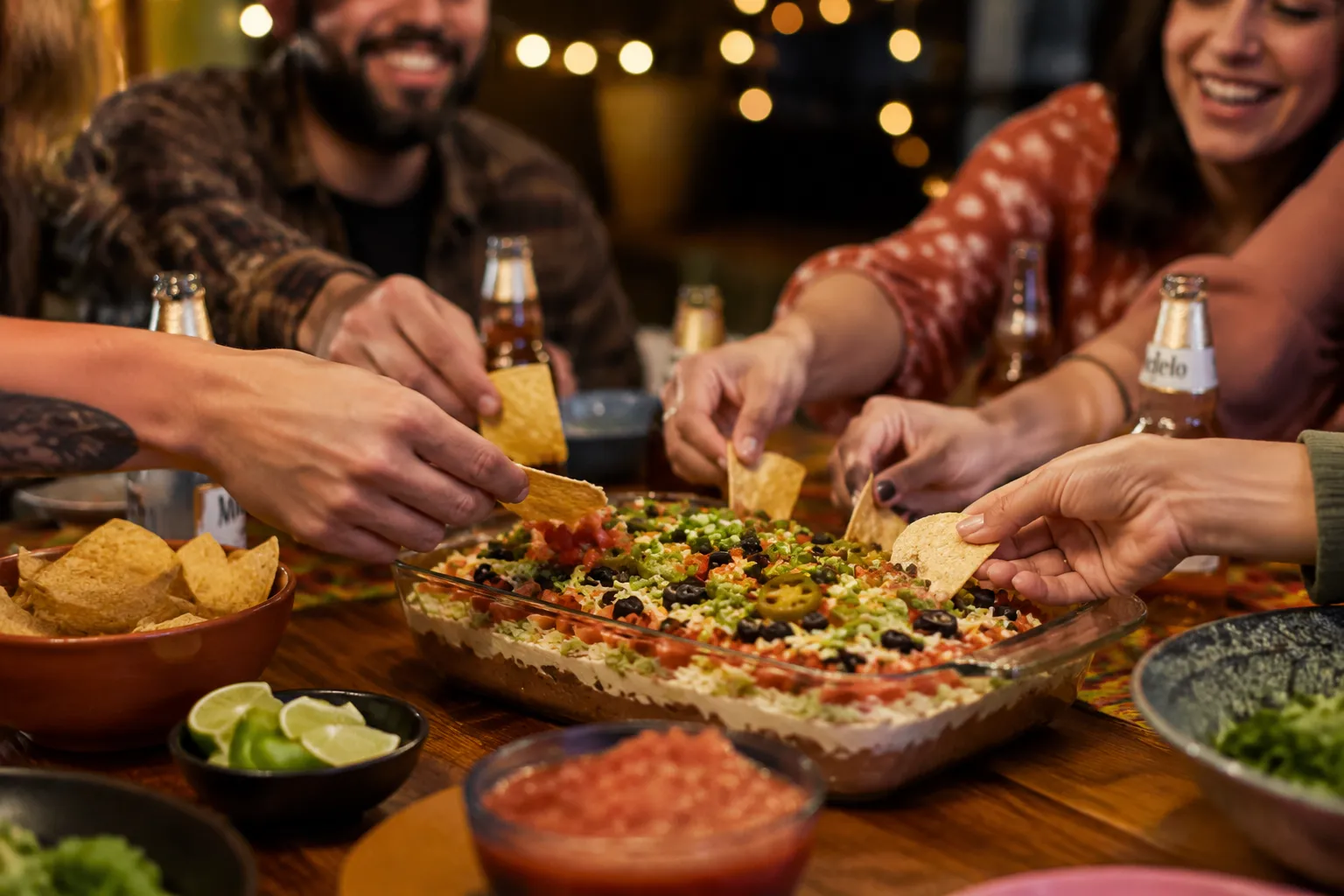 Friends sharing layered taco dip at a game day party