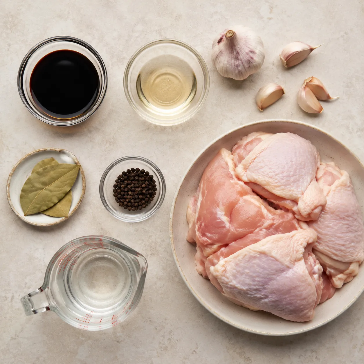 Ingredients for chicken adobo recipe including soy sauce vinegar garlic and bay leaves