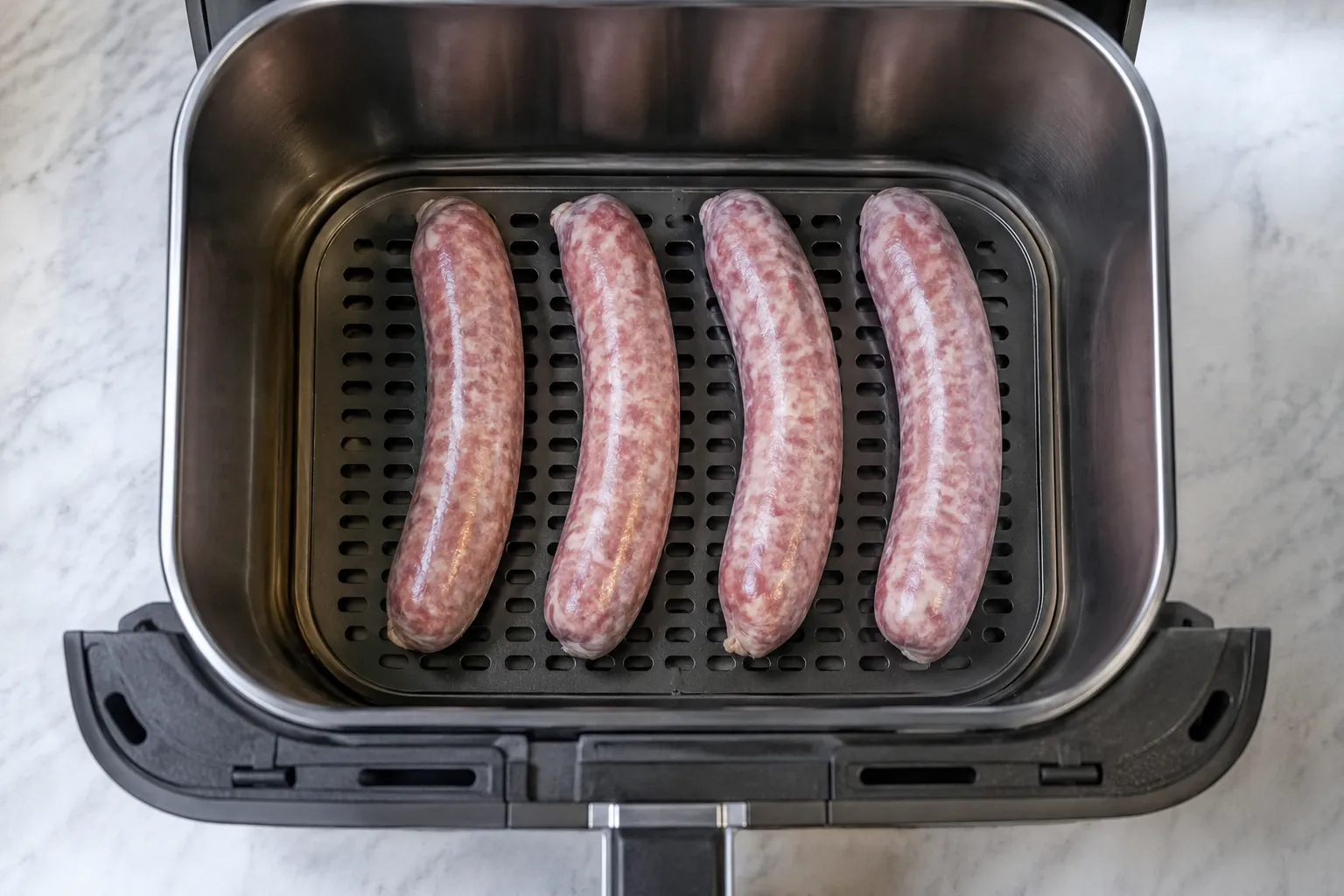 Raw brats arranged in a single layer in the air fryer basket