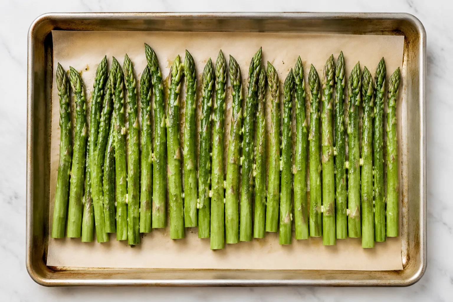 Asparagus spears tossed with olive oil and garlic on a sheet pan before roasting