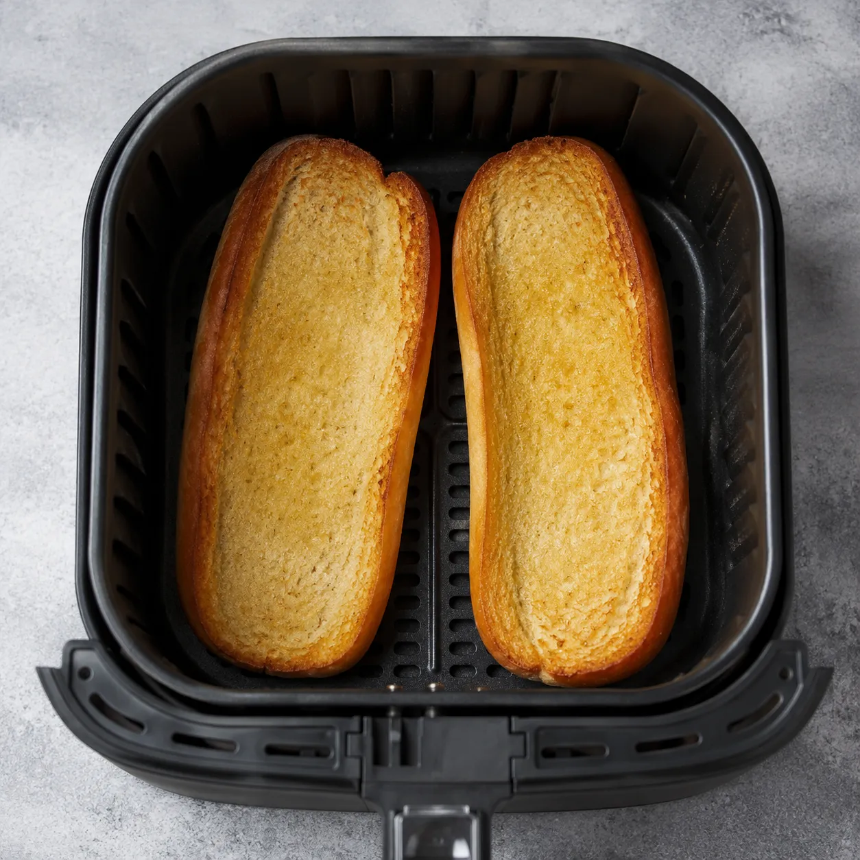 Toasted hot dog buns in air fryer basket ready for assembly