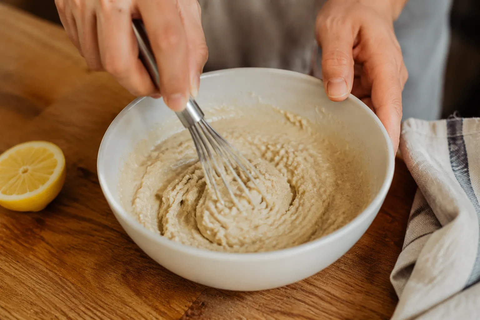 Whisking tahini and lemon juice as the sauce seizes and thickens