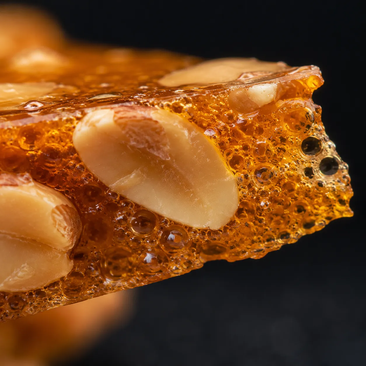 Close-up texture of crispy peanut brittle showing aerated bubbles