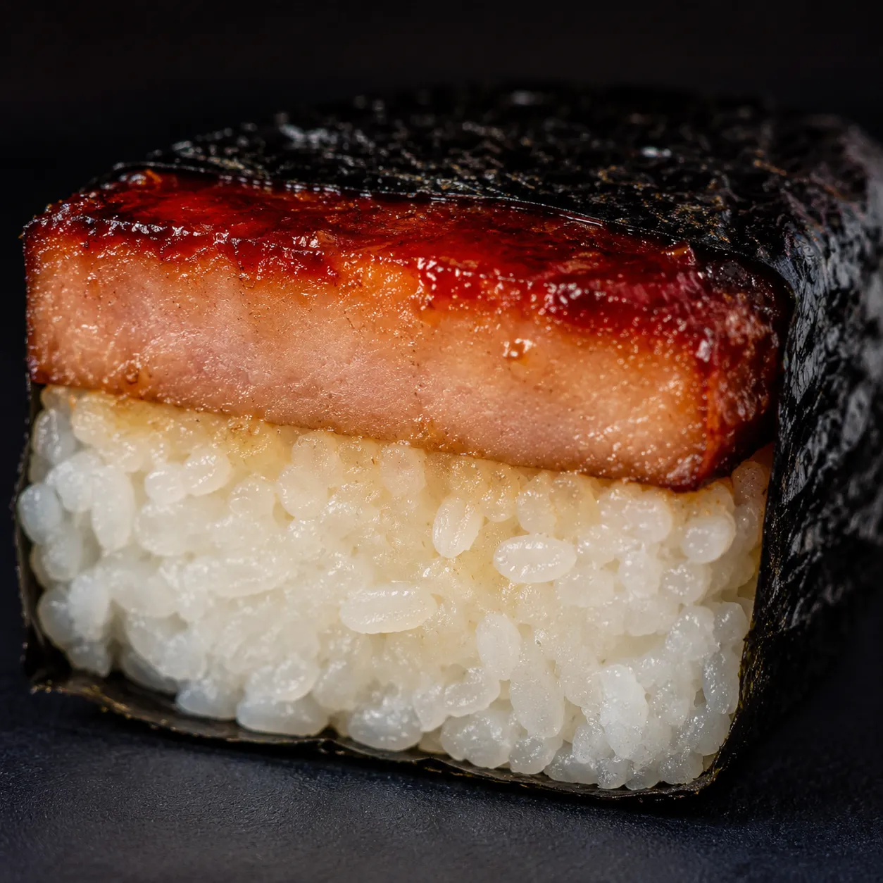 Macro close-up of a musubi cross-section with rice, Spam, and nori