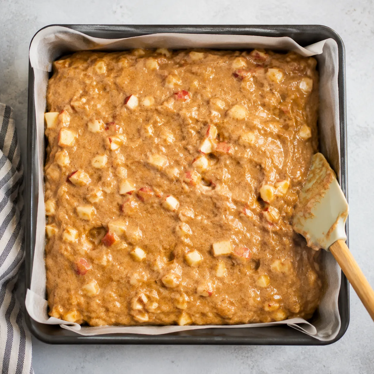 Apple cake batter in a square baking pan ready to bake