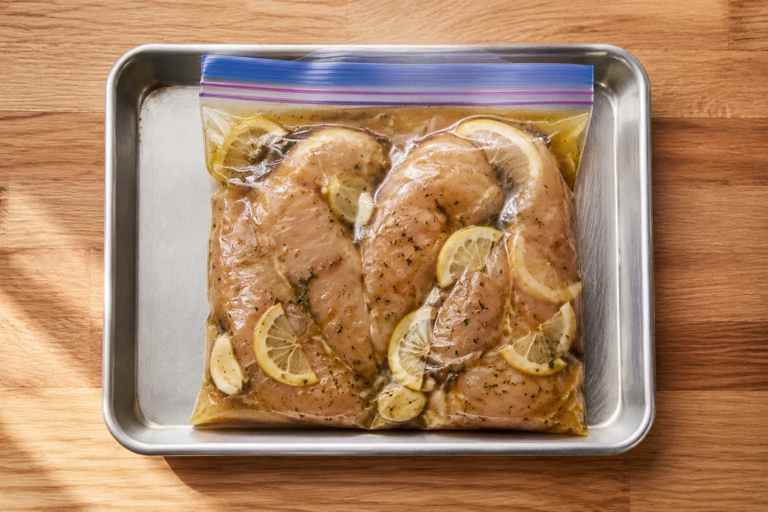 Chicken breasts marinating in a zip-top bag with lemon and garlic