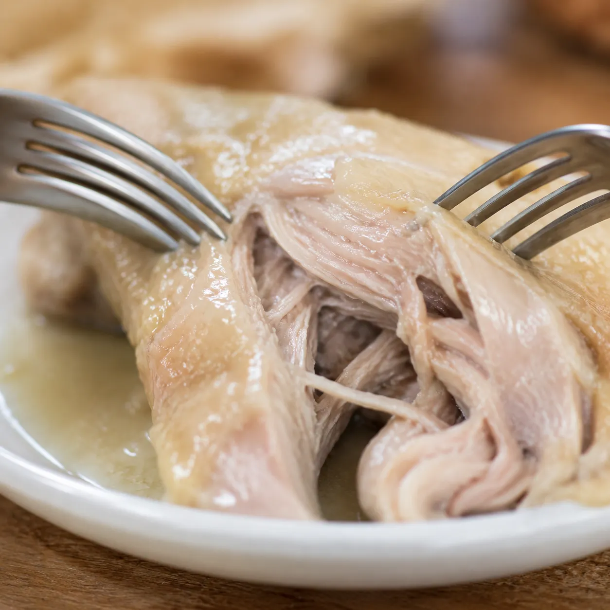 Shredding poached chicken with two forks for Italian penicillin soup