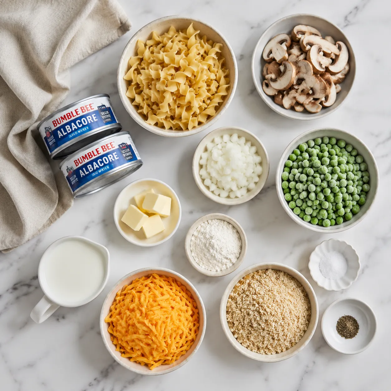 Tuna casserole ingredients flatlay with egg noodles, albacore tuna, mushrooms, and cheddar