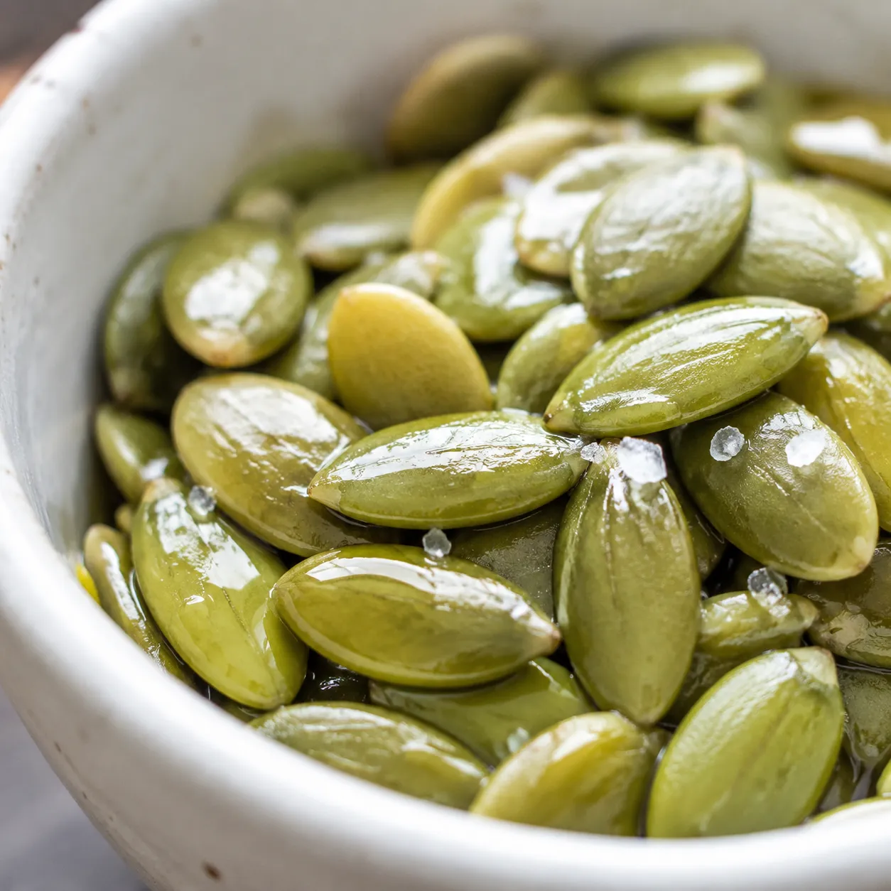 Close-up of raw pumpkin seeds tossed with oil and salt for a pumpkin seed recipe