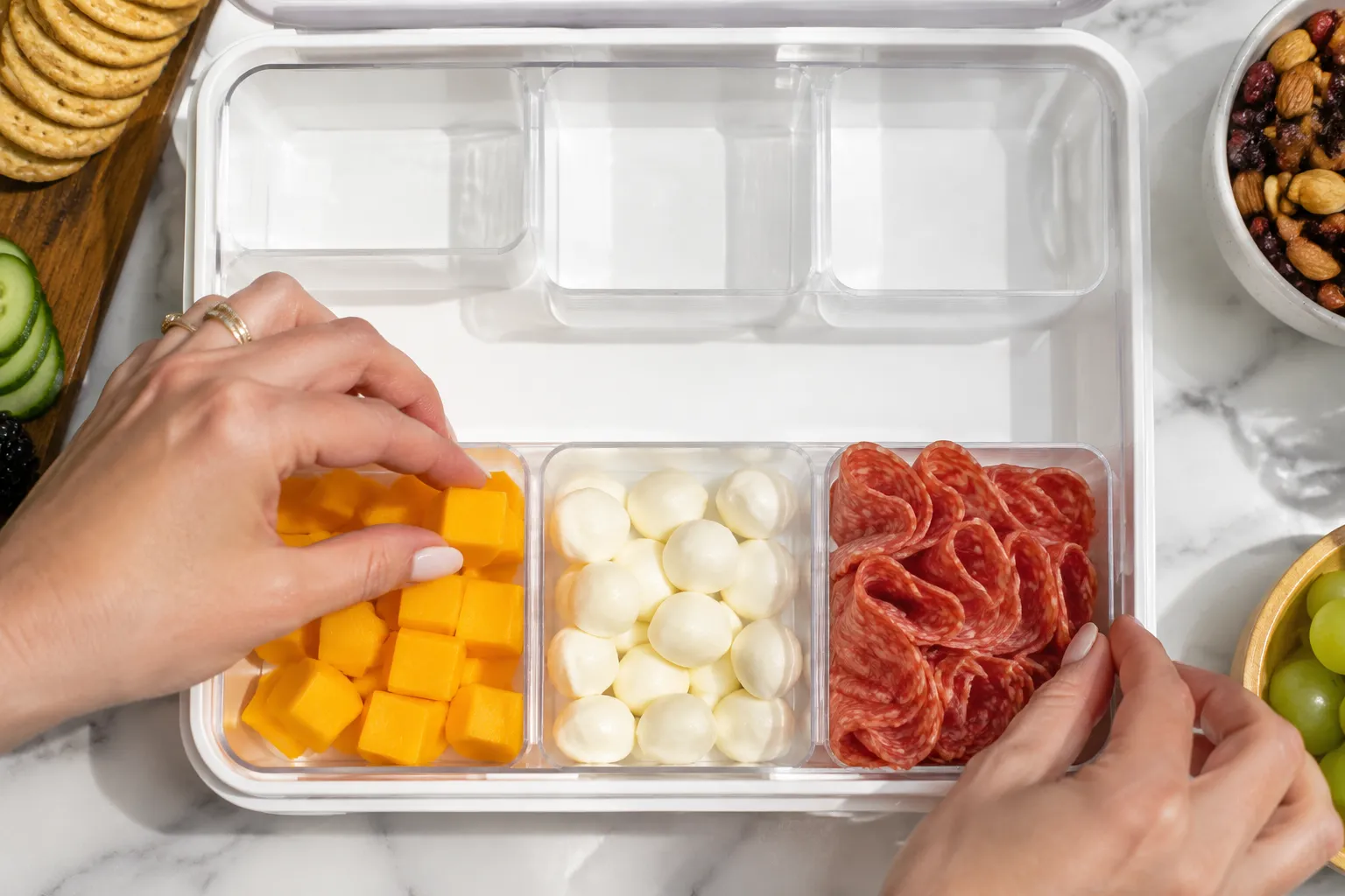 Filling snackle box compartments with cheese and cured meats