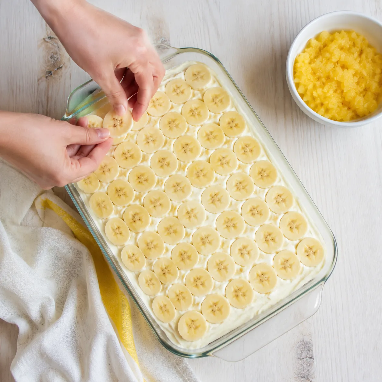 Layering fresh banana slices over cream cheese for banana split cake