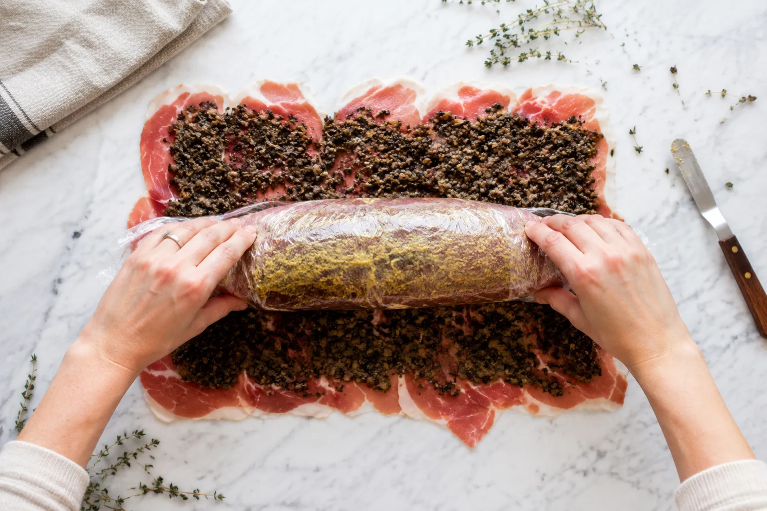 Wrapping beef tenderloin in prosciutto and duxelles for beef wellington recipe