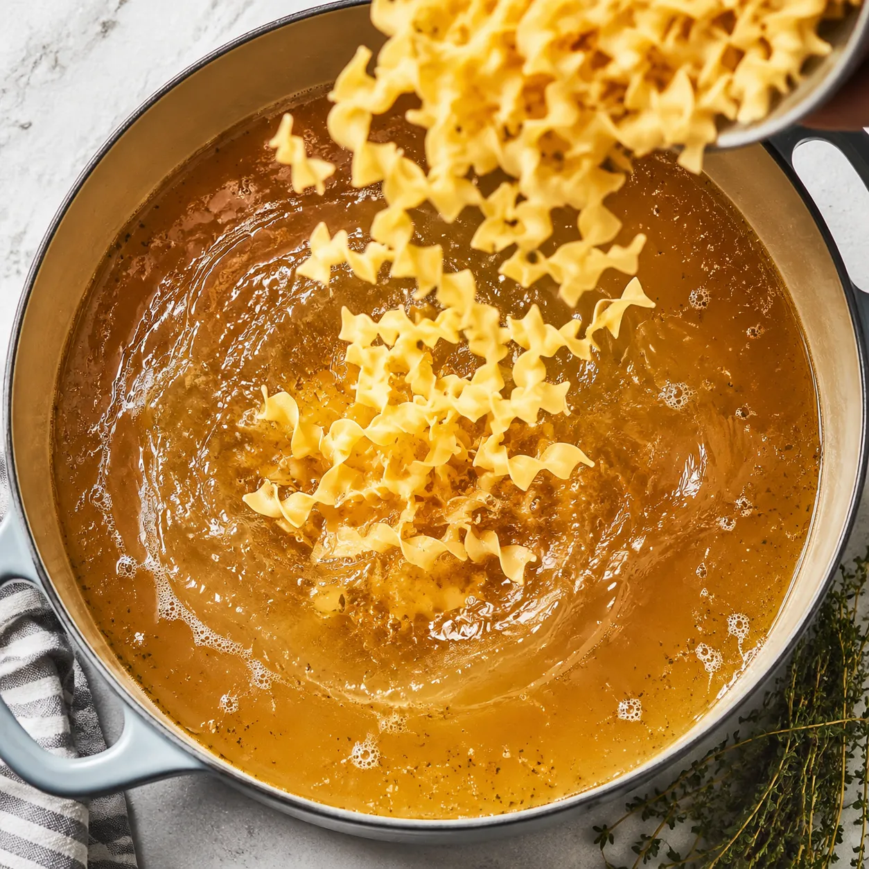 Adding egg noodles to chicken broth for chicken noodles