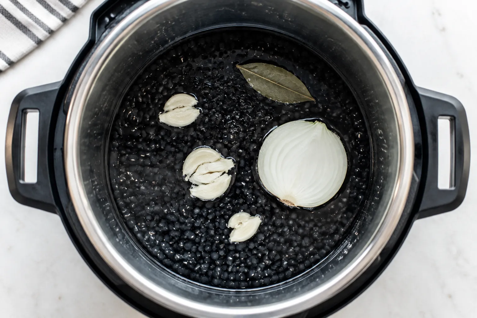 Black beans and aromatics added to the Instant Pot before pressure cooking