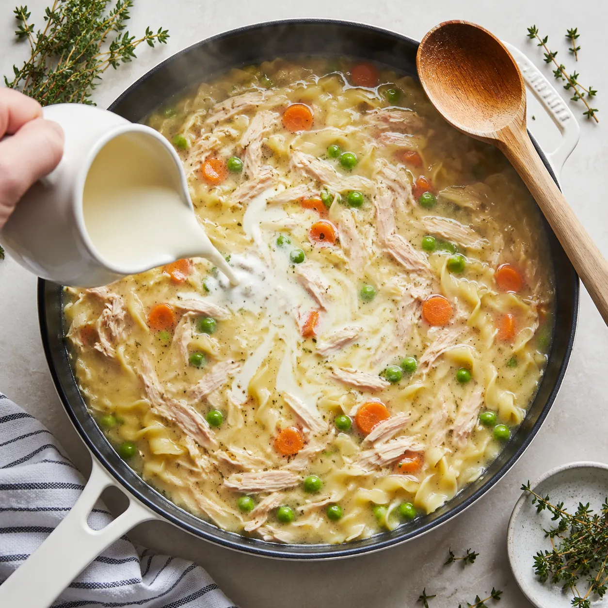 Pouring cream into a leftover turkey noodle skillet