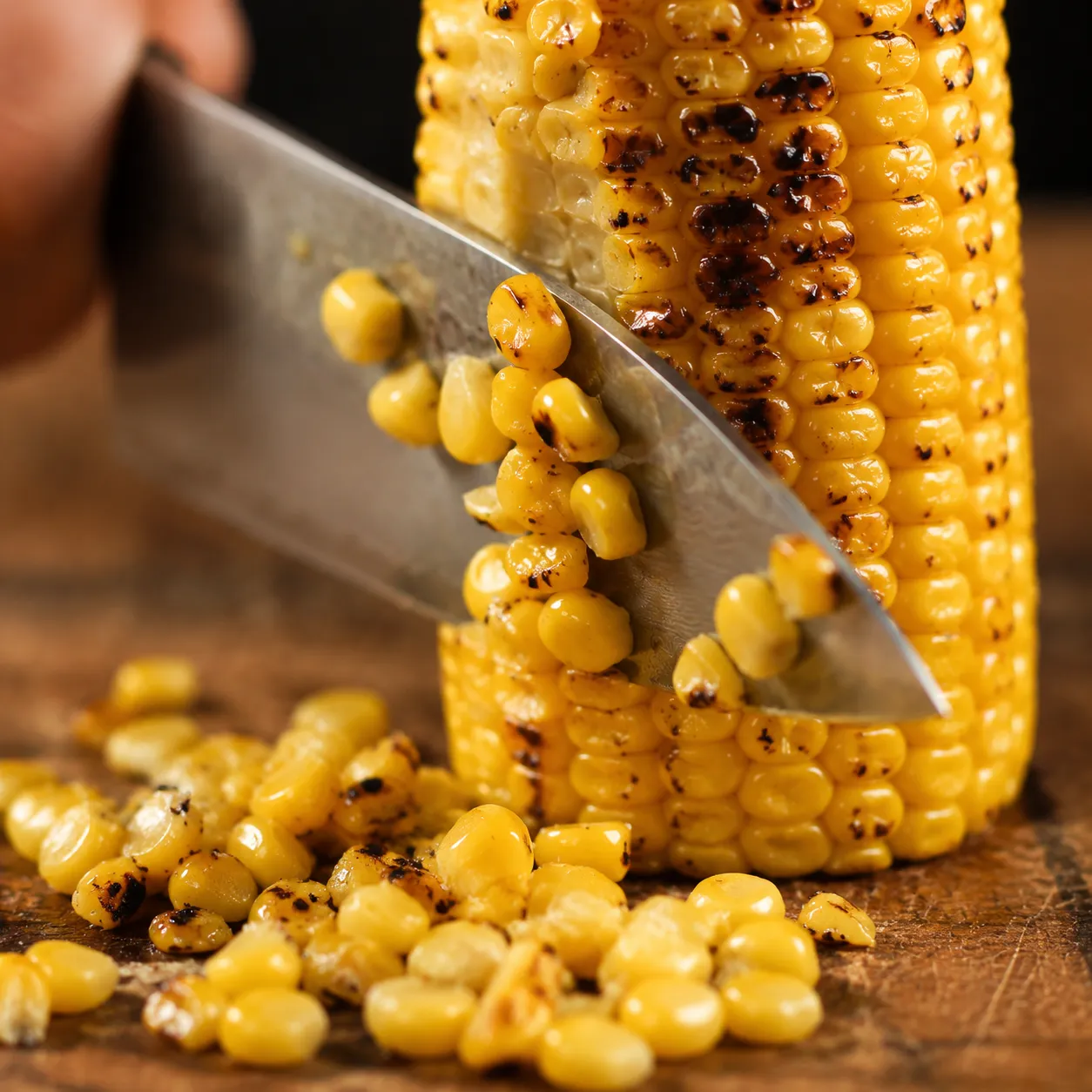 Cutting kernels off charred corn cob for homemade corn salsa