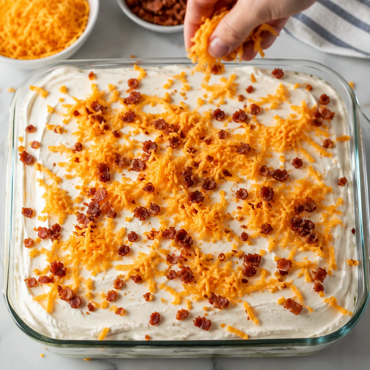 Topping a layered salad with sharp cheddar cheese and bacon