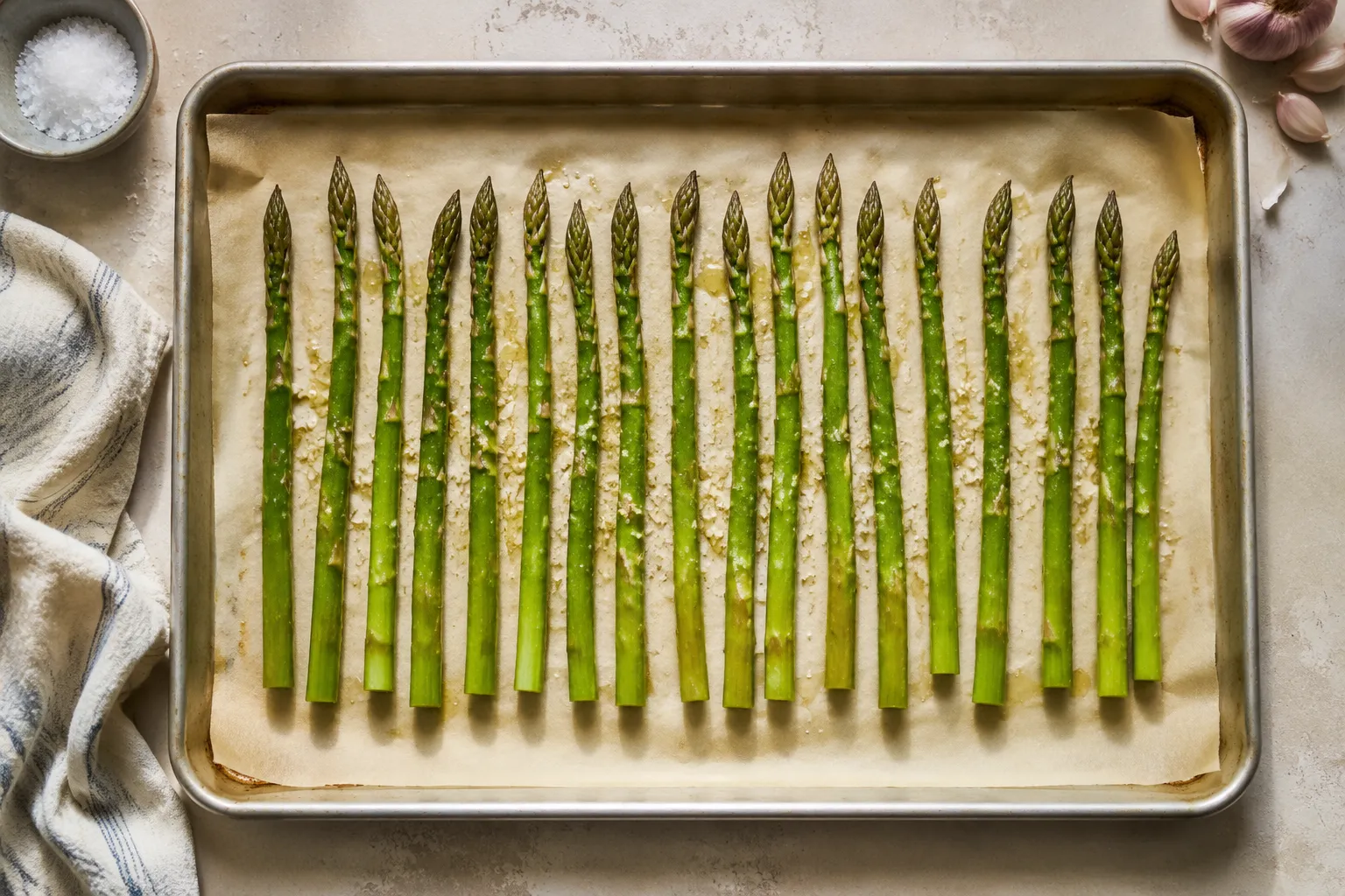 Asparagus spears seasoned with olive oil and garlic on a sheet pan
