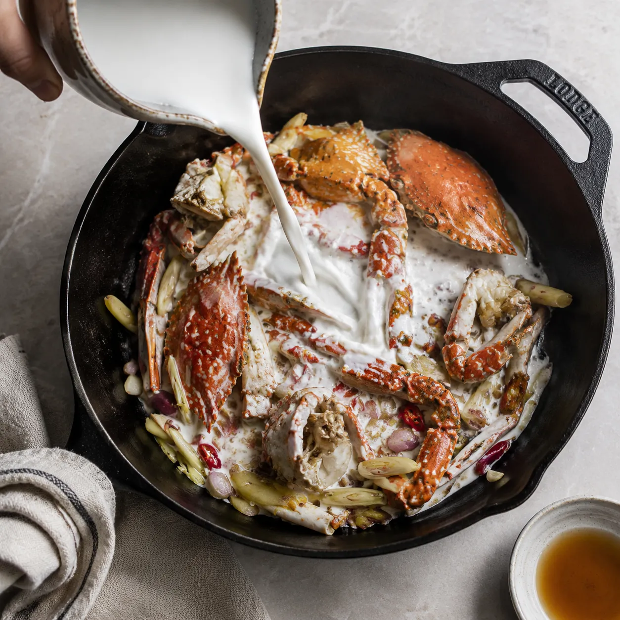 Pouring coconut milk over crab for ginataang alimasag