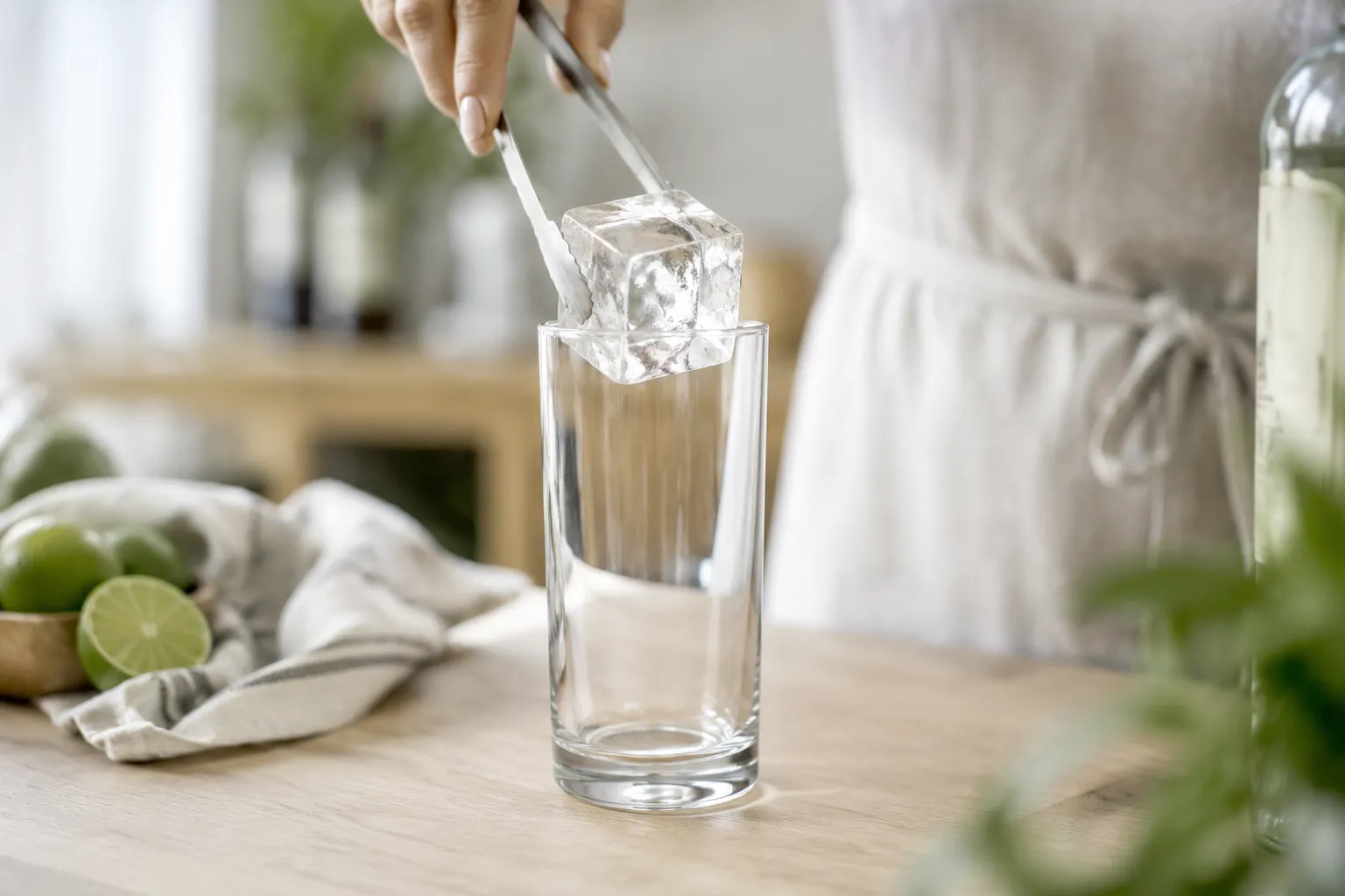Adding ice cubes to a highball glass to build a dirty Shirley cocktail