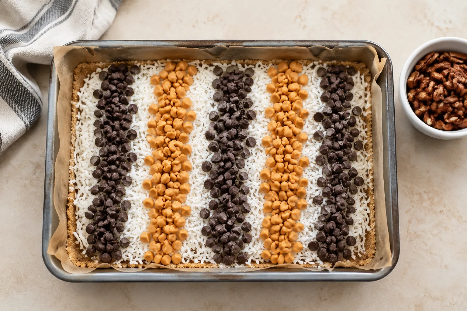 Layering chocolate chips, butterscotch, and coconut for seven layer bars