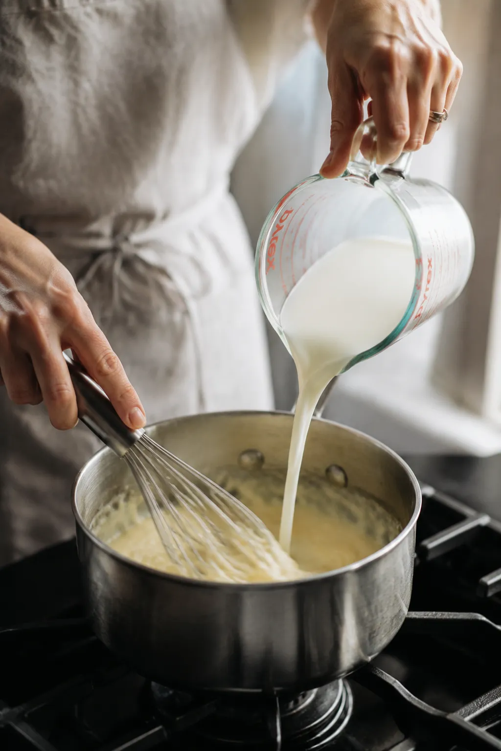 Whisking warm milk into roux to make homemade white sauce