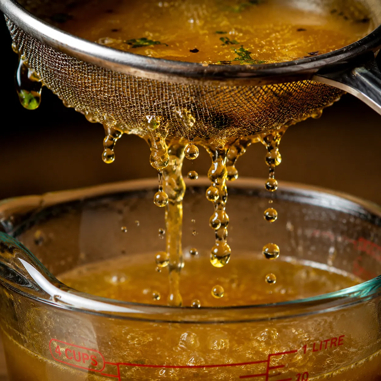 Straining homemade chicken broth through a fine mesh sieve