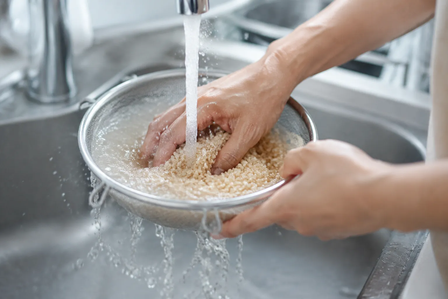 Rinsing brown rice in a fine mesh strainer before cooking