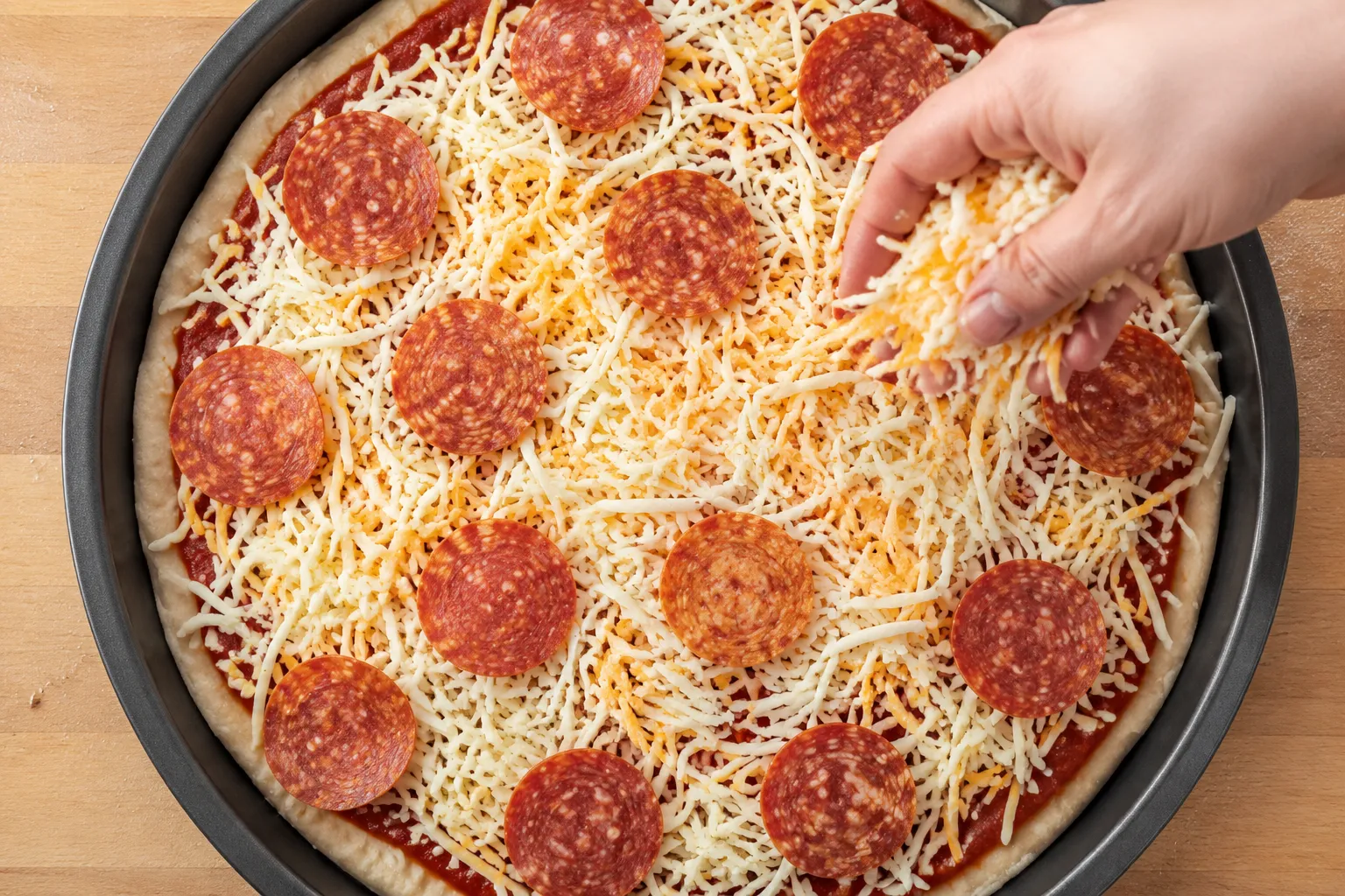 Adding muenster cheese and pepperoni to raw pizza