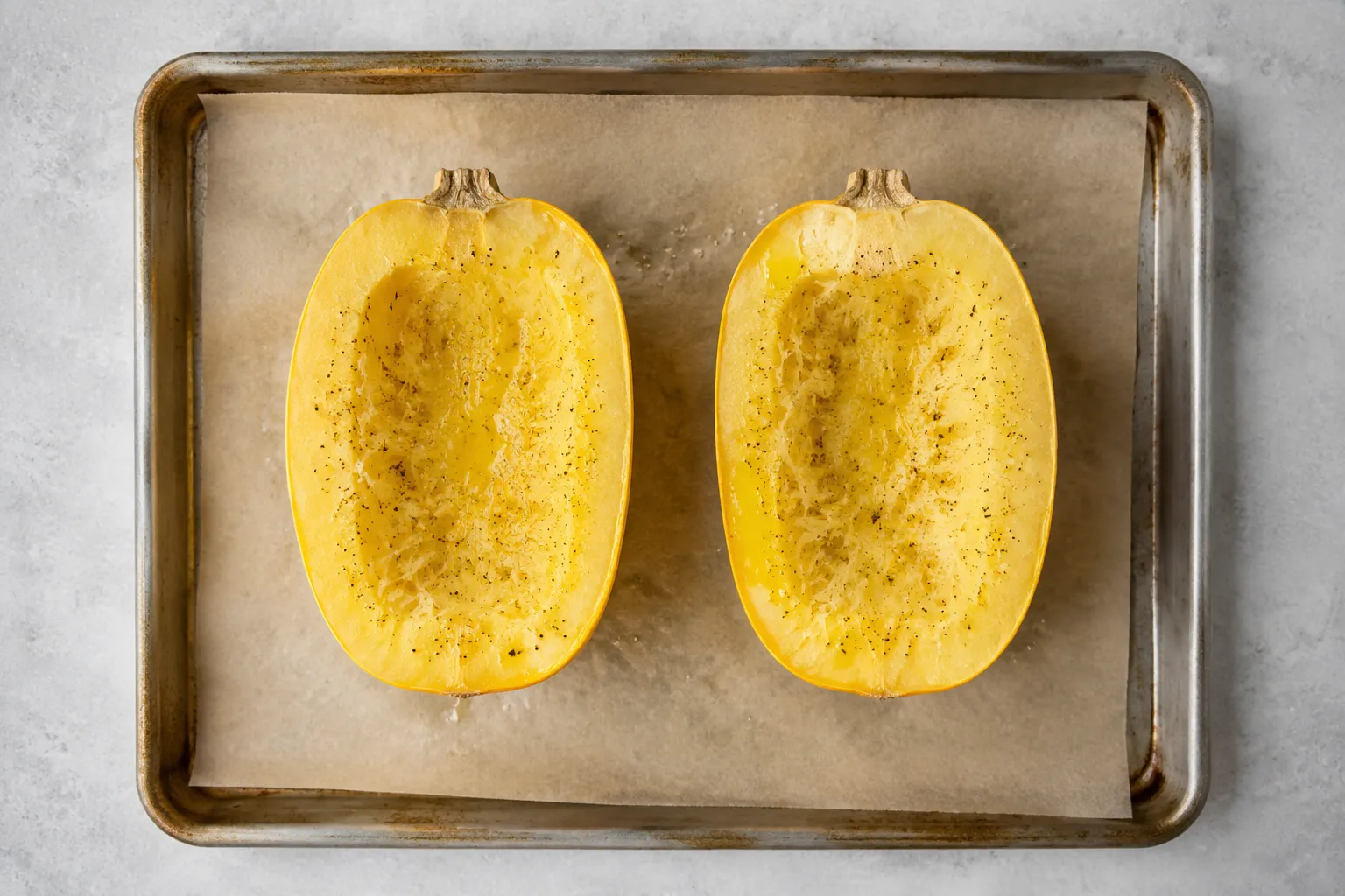 Spaghetti marrow halves seasoned with olive oil on a sheet pan