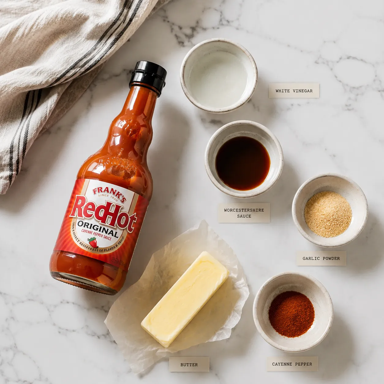 Ingredients for homemade buffalo sauce recipe arranged on a marble countertop.