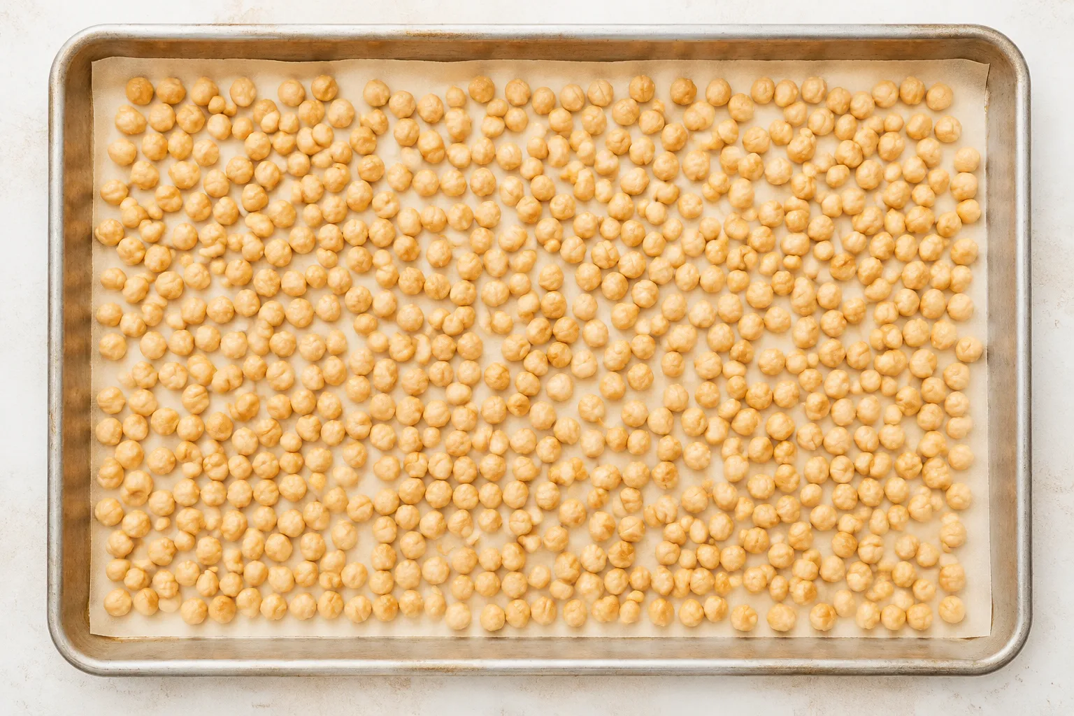 Baked chickpeas spread on sheet pan before second roast