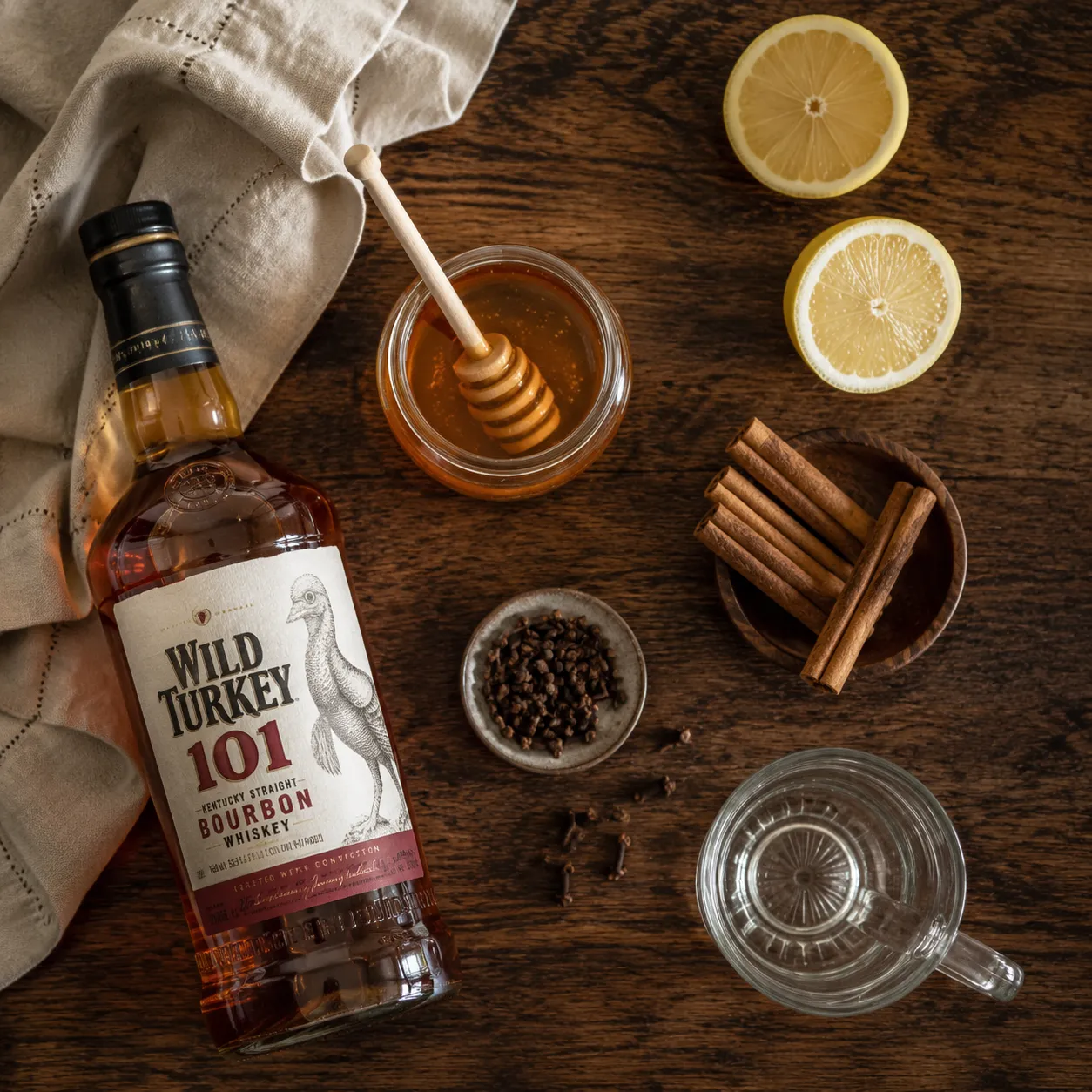 Hot whisky toddy ingredients flatlay with bourbon, honey, lemon, and spices
