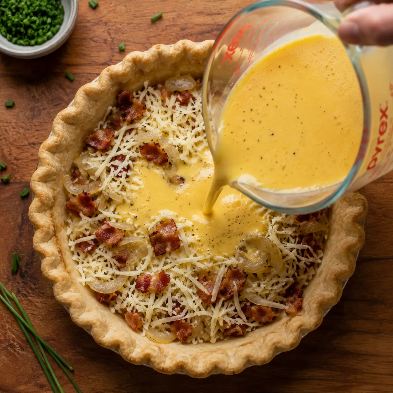 Pouring custard into pie crust to make easy quiche recipe